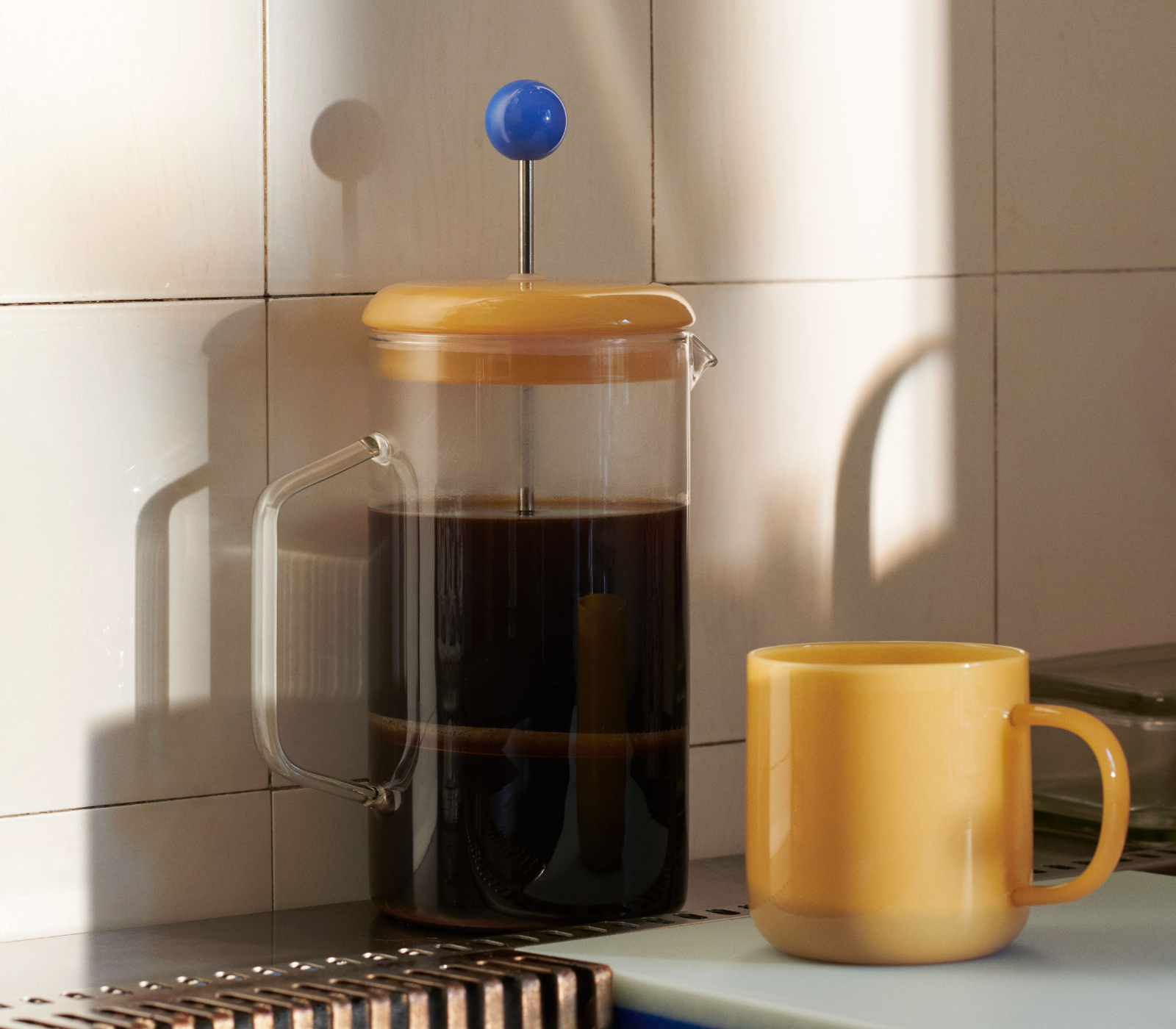 French Press Brewer Clear en cocina con taza de café French press Brewer Clear de cristal con café en una cocina junto a una taza